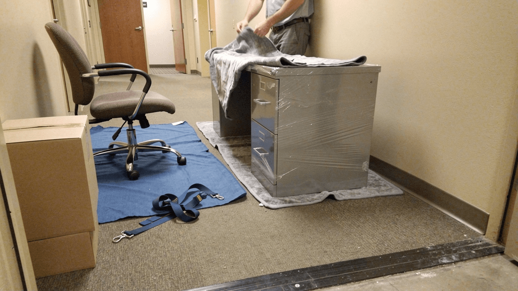 Office desks and wrapped workplace furniture prepared for a San Angelo office move